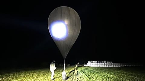 An undated photo shows an officer inspecting a balloon used to carry cigarettes into Lithuania.