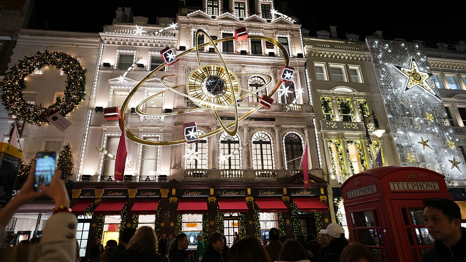 FILE. Pedestrians photograph stores with Christmas lights on Bond Street in London. 19 Dec. 2024.