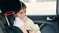A child coughs into his hand in the car.