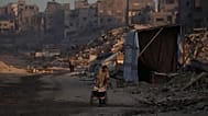 فلسطينيون يسيرون وسط الدمار الذي خلّفته الهجمات الجوية والبرية الإسرائيلية في حي الشيخ رضوان بمدينة غزة، الأربعاء 22 تشرين الأول/أكتوبر 2025.