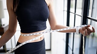 امرأة تقيس محيط خصرها بشريط قياس