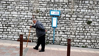 في هذه الصورة الملتقطة يوم الثلاثاء، 14 مايو/أيار 2019، يظهر رجل مسن يصعد تلة في بلدة كاربينيسي، بمنطقة إيفريتانيا، وسط اليونان.