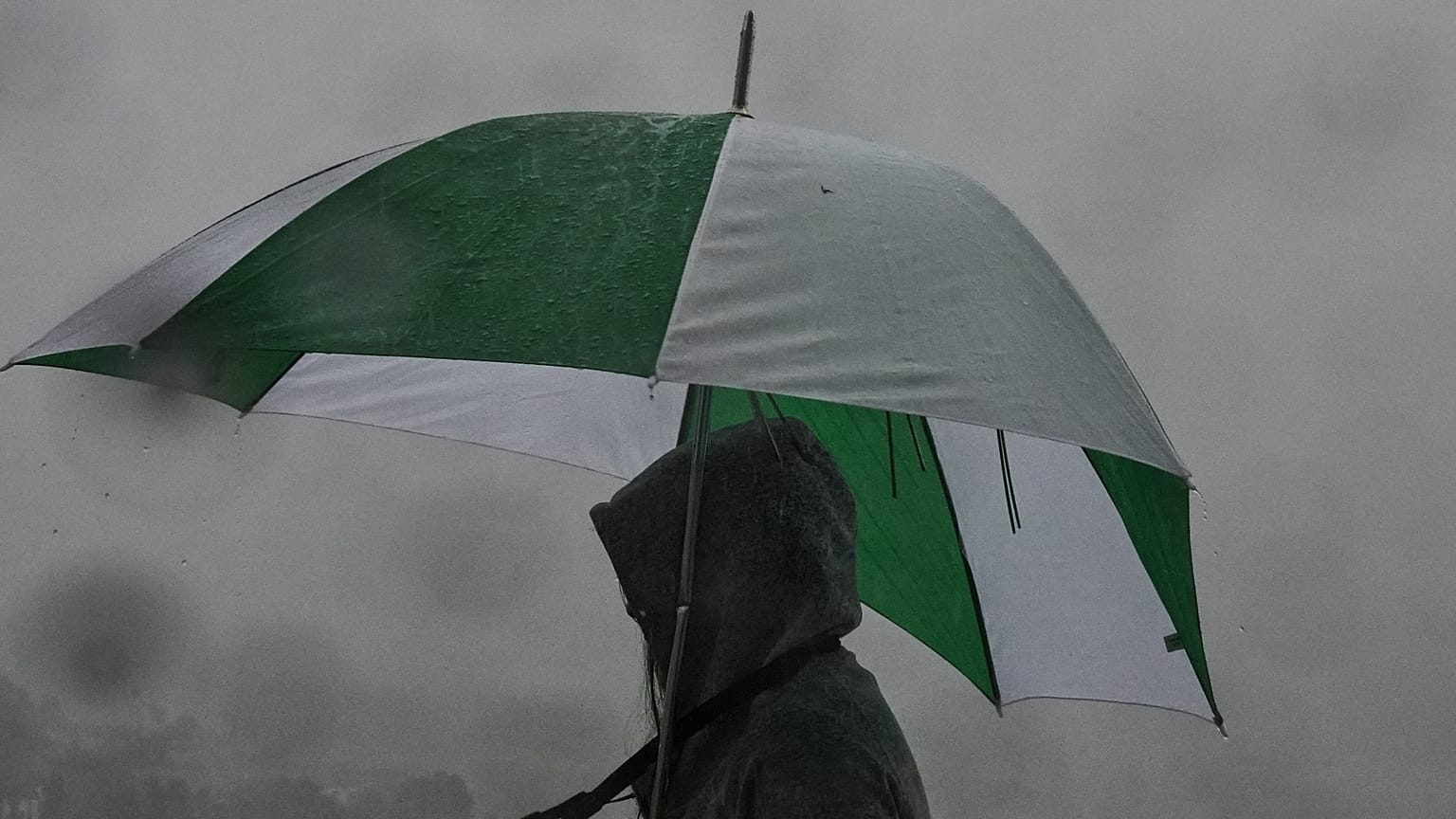 Ein Besucher schützt sich mit einem Regenschirm an einem Aussichtspunkt beim Griffith Park Observatory während eines Sturms am Dienstag, den 14. Oktober 2025, in Los Angeles