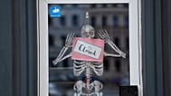 A skeleton and a sign with the inscription "Closed" hang in the door of a closed shop in Berlin, Germany. 2 Nov. 2020.