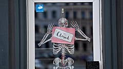 Un esqueleto y un cartel con la inscripción 'Cerrado' cuelgan de la puerta de una tienda en Berlín, Alemania. el 2 de noviembre de 2020