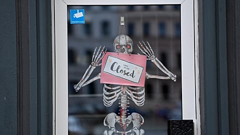 A skeleton and a sign with the inscription "Closed" hang in the door of a closed shop in Berlin, Germany. 2 Nov. 2020.