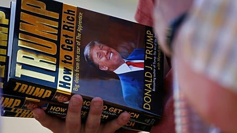صورة تعبيرية لأحد مناصري ترامب يحمل كتاب كيف تصبح غنياً؟