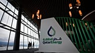 Delegates are silhouetted as they take in the view of the harbour while talking near the Qatar Energy booth during the opening ceremony at the LNG2023 conference