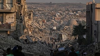 فلسطينيون يسيرون وسط الدمار الذي خلفته الغارات الجوية والأرضية الإسرائيلية على مدينة غزة، الخميس 23 أكتوبر/تشرين الأول 2025.