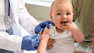 A health worker prepares to give a baby a vaccine.