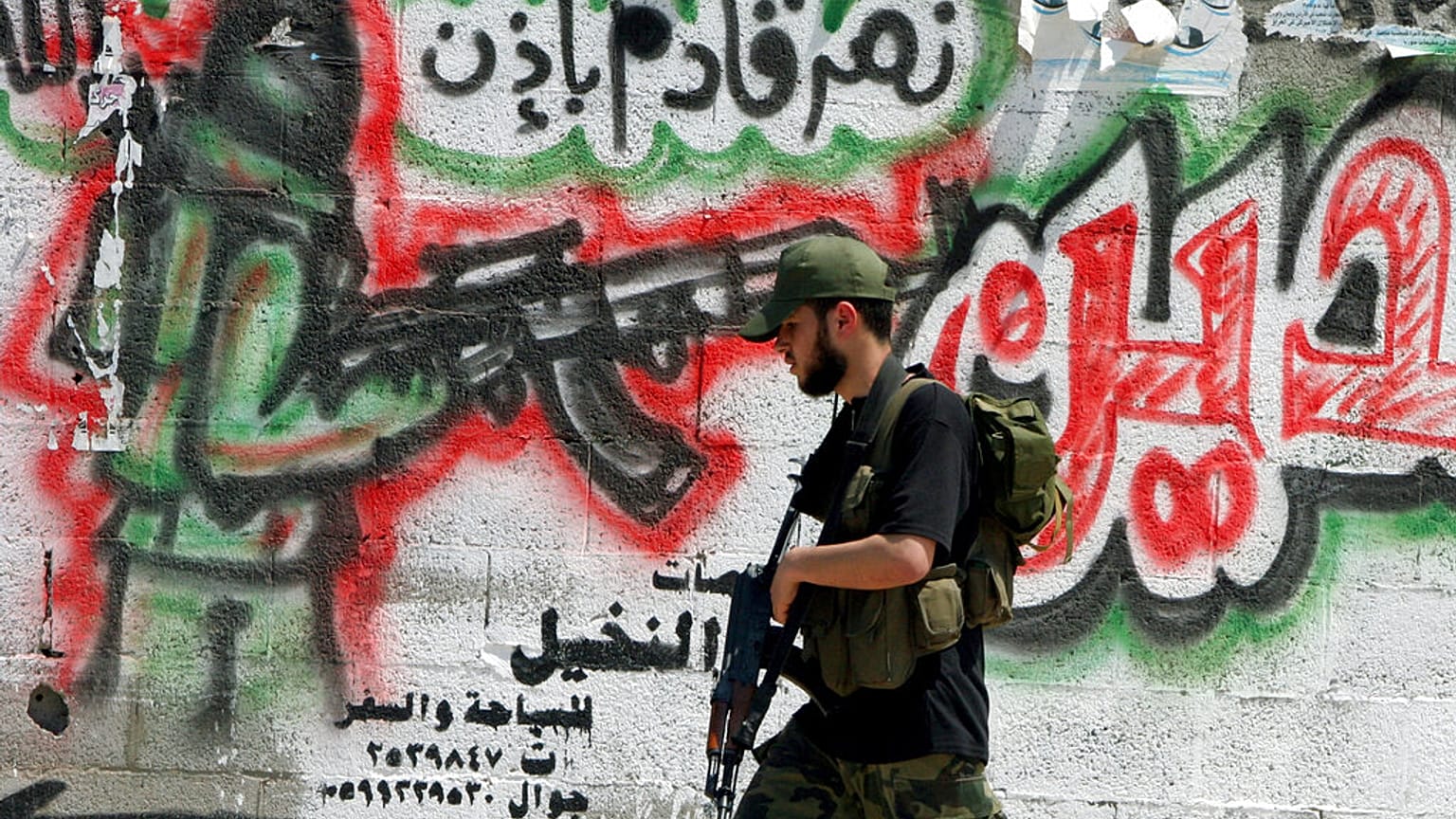  مسلح فلسطيني من قوات الامن التابعة لحكومة حماس يمر من أمام جدار في أحد شوارع مخيم دير البلح في قطاع غزة 17 مايو 2006