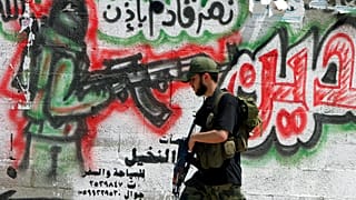  مسلح فلسطيني من قوات الامن التابعة لحكومة حماس يمر من أمام جدار في أحد شوارع مخيم دير البلح في قطاع غزة 17 مايو 2006