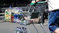 A man pushes a shopping cart outside a supermarket. Photo by Martin Meissner.