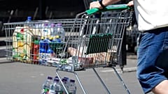 A man pushes a shopping cart outside a supermarket. Photo by Martin Meissner.