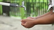 A boy washing his hands from an outdoor tap.