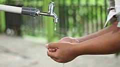 Un garçon se lave les mains à un robinet extérieur.