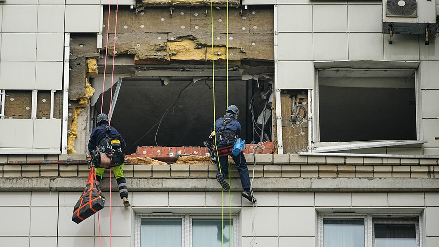 موظفو البلدية يعملون على جانب مبنى سكني متعدد الطوابق تعرض لهجوم بطائرة بدون طيار أوكرانية في كراسنوجورسك، على مشارف موسكو