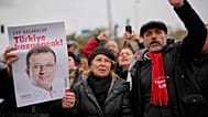 İnsanlar, Ekrem İmamoğlu’nun İstanbul’da gözaltına alındıktan sonra götürüldüğü Vatan Emniyet Müdürlüğü binası önünde İmamoğlu'nun posterlerini taşıyor, 19 Mart 2025