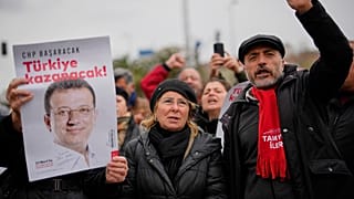 İnsanlar, Ekrem İmamoğlu’nun İstanbul’da gözaltına alındıktan sonra götürüldüğü Vatan Emniyet Müdürlüğü binası önünde İmamoğlu'nun posterlerini taşıyor, 19 Mart 2025