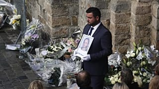 Un employé des pompes funèbres tient un portrait de l'écolière de 12 ans, connue sous le nom de Lola, à la fin de la cérémonie funéraire, à l'extérieur de l'église de Lillers, dans le nord de la France, en 2022.
