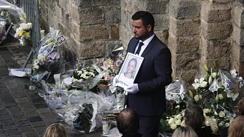 A funeral worker holds a portrait of the 12-year-old schoolgirl, known as Lola, at the end of her funeral ceremony, outside the church of Lillers, northern France in 2022