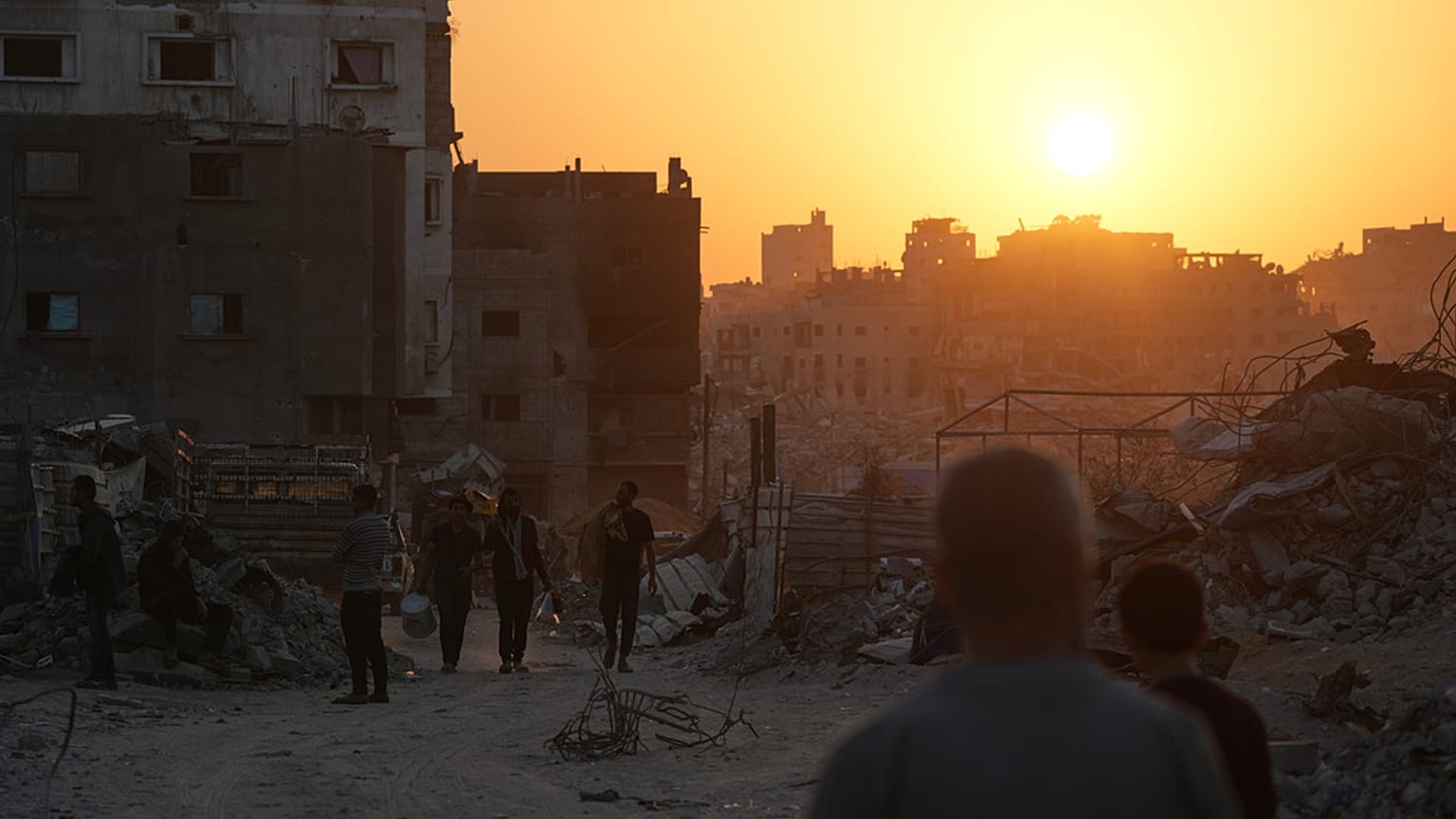 فلسطينيون يسيرون بين الدمار الذي خلفته الهجمات الجوية والأرضية الإسرائيلية على مدينة غزة، الخميس 23 أكتوبر/تشرين الأول 2025