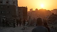 فلسطينيون يسيرون بين الدمار الذي خلفته الهجمات الجوية والأرضية الإسرائيلية على مدينة غزة، الخميس 23 أكتوبر/تشرين الأول 2025