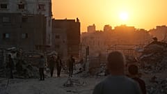 فلسطينيون يسيرون بين الدمار الذي خلفته الهجمات الجوية والأرضية الإسرائيلية على مدينة غزة، الخميس 23 أكتوبر/تشرين الأول 2025