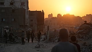 فلسطينيون يسيرون بين الدمار الذي خلفته الهجمات الجوية والأرضية الإسرائيلية على مدينة غزة، الخميس 23 أكتوبر/تشرين الأول 2025