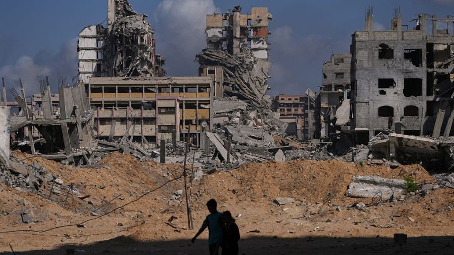فلسطينيون يسيرون وسط الدمار الذي خلفته الغارات الجوية والأرضية الإسرائيلية في مخيم الشاطئ في مدينة غزة، الجمعة 24 أكتوبر/تشرين الأول 2025.