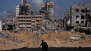 فلسطينيون يسيرون وسط الدمار الذي خلفته الغارات الجوية والأرضية الإسرائيلية في مخيم الشاطئ في مدينة غزة، الجمعة 24 أكتوبر/تشرين الأول 2025.