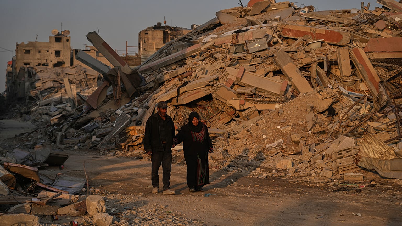 فلسطينيون يسيرون في حوض الدمار الناجم عن الهجوم الجوي والبري الإسرائيلي في مدينة غزة, الخميس, أكتوبر. 23, 2025.