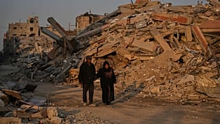 فلسطينيون يسيرون في حوض الدمار الناجم عن الهجوم الجوي والبري الإسرائيلي في مدينة غزة, الخميس, أكتوبر. 23, 2025. 