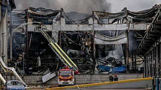 Um elétrico público passa contra o fundo de fumo crescente durante o ataque maciço de drones e mísseis da Rússia em Kiev, Ucrânia, no domingo, 28 de setembro de 2025