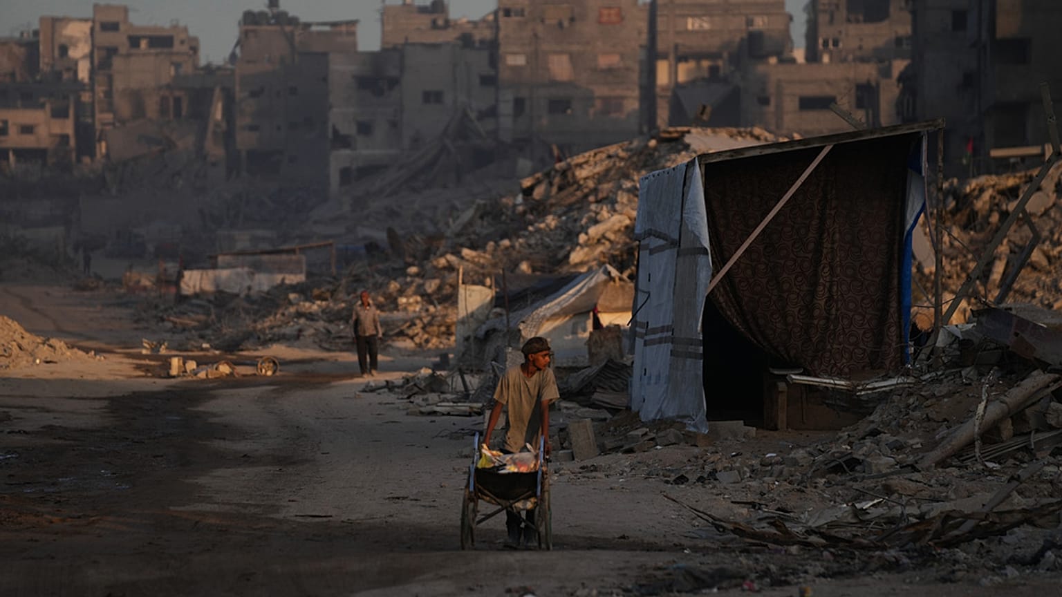 فلسطينيون يسيرون في محيط الدمار الناجم عن الهجوم الجوي والبري الإسرائيلي في حي الشيخ رضوان في مدينة غزة, الأربعاء, أكتوبر. 22, 2025.