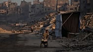 فلسطينيون يسيرون في محيط الدمار الناجم عن الهجوم الجوي والبري الإسرائيلي في حي الشيخ رضوان في مدينة غزة, الأربعاء, أكتوبر. 22, 2025.