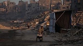 فلسطينيون يسيرون في محيط الدمار الناجم عن الهجوم الجوي والبري الإسرائيلي في حي الشيخ رضوان في مدينة غزة, الأربعاء, أكتوبر. 22, 2025.