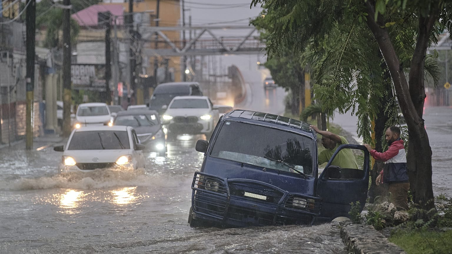 Des personnes abandonnent une voiture dans une rue impraticable inondée par les pluies causées par la tempête tropicale Melissa à Saint-Domingue, en République dominicaine