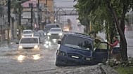 Des personnes abandonnent une voiture dans une rue impraticable inondée par les pluies causées par la tempête tropicale Melissa à Saint-Domingue, en République dominicaine