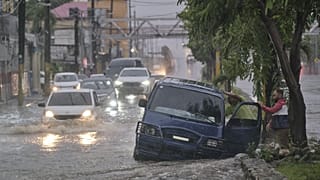 Des personnes abandonnent une voiture dans une rue impraticable inondée par les pluies causées par la tempête tropicale Melissa à Saint-Domingue, en République dominicaine