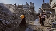 فلسطينيون يسيرون بين أنقاض مدينة غزة، الأحد 26 أكتوبر.
