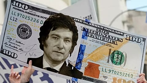 Javier Milei trzyma gigantyczny karton przedstawiający banknot 100 dolarowy z jego twarzą podczas wiecu we wrześniu 2023 roku.