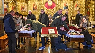 Kiev'deki Aziz Michael Manastırı’nda düzenlenen cenaze töreninde gazetecilerin tabutları başında yas tutan insanlar, 27 Ekim 2025