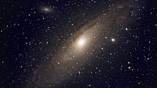 في هذه الصورة التي التقطها تلسكوب، يرسم قمر صناعي أثرًا على شكل خط مستقيم وهو يمر أمام خلفية مجرة أندروميدا، فوق قرية بودوليه في روسيا (أ.ف.ب/ ديميتري لوفيسكي)