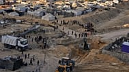  فلسطينيون يشاهدون آلات وبعض العمال من مصر يبحثون عن جثث الرهائن في مدينة حمد، في خان يونس، جنوب قطاع غزة