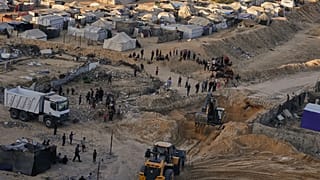  فلسطينيون يشاهدون آلات وبعض العمال من مصر يبحثون عن جثث الرهائن في مدينة حمد، في خان يونس، جنوب قطاع غزة