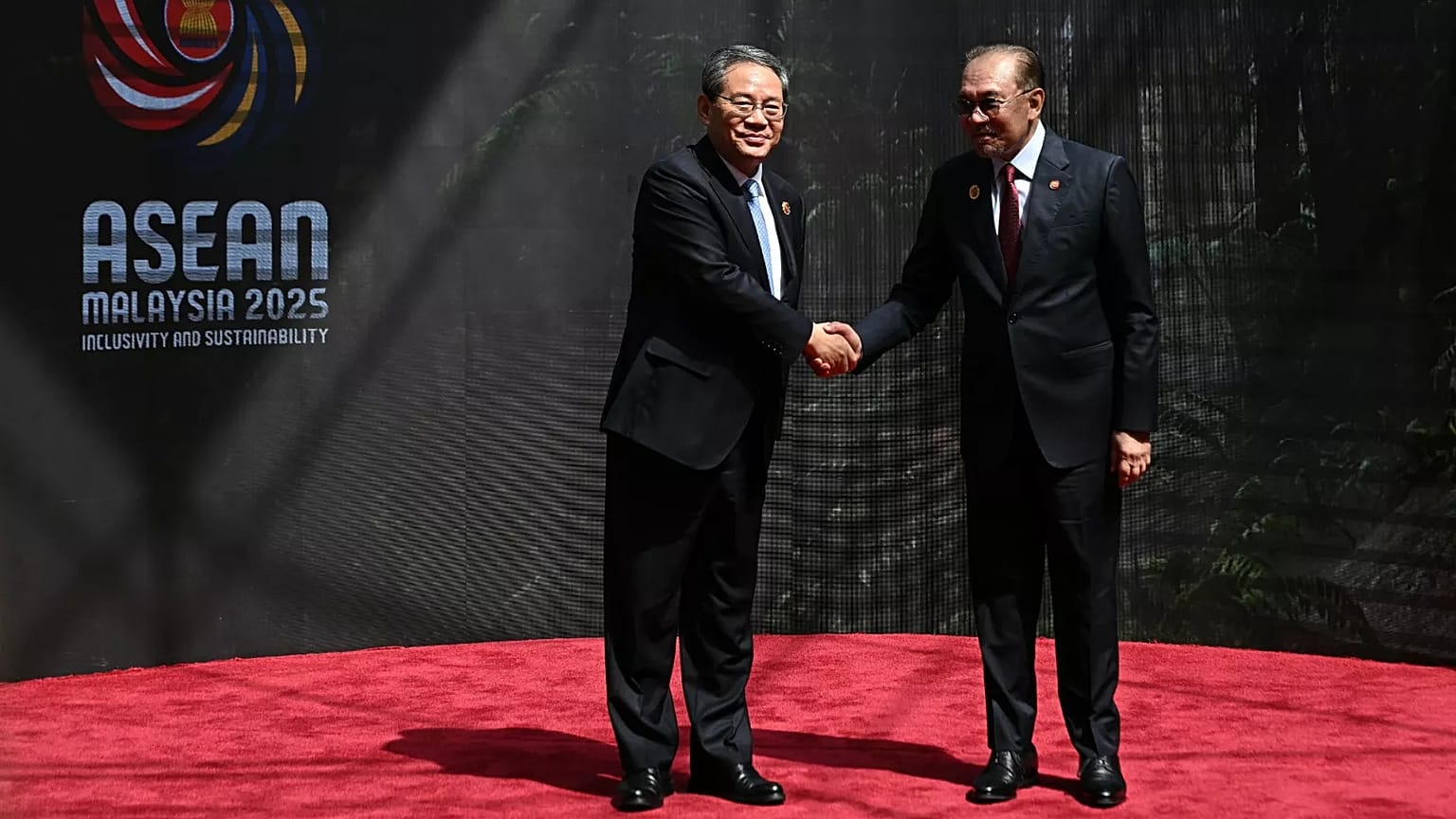 China's Premier Li Qiang, left, shakes hands with Malaysia's Prime Minister Anwar Ibrahim as he arrives at the Kuala Lumpur Convention Centre,  Monday, Oct. 27, 2025.