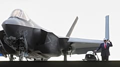الرئيس دونالد ترامب يسير بجانب مقاتلة من طراز F/A-18 نحو المنصة قبل إلقاء كلمته على أعضاء الجيش على متن حاملة الطائرات USS George Washington، الراسية في قاعدة بحرية أمريكية