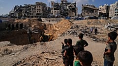 In Hamad City in Chan Yunis suchen ägyptische Baumaschinen und Arbeiter nach den Leichen von Geiseln. Palästinenser sehen zu.