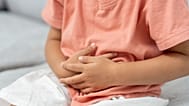 A toddler holds their stomach.